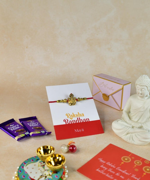 Sowpeace Exquisite Golden Ganesha Rakhi Pack of 1 with Roli Chawal Thali, Chocolates, Buddha and Greeting card combo for Raksha Bandhan and Gifting